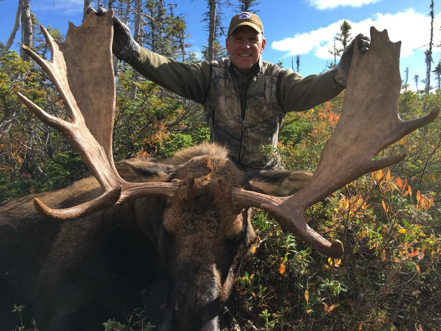 Man holding the antlers of a moose