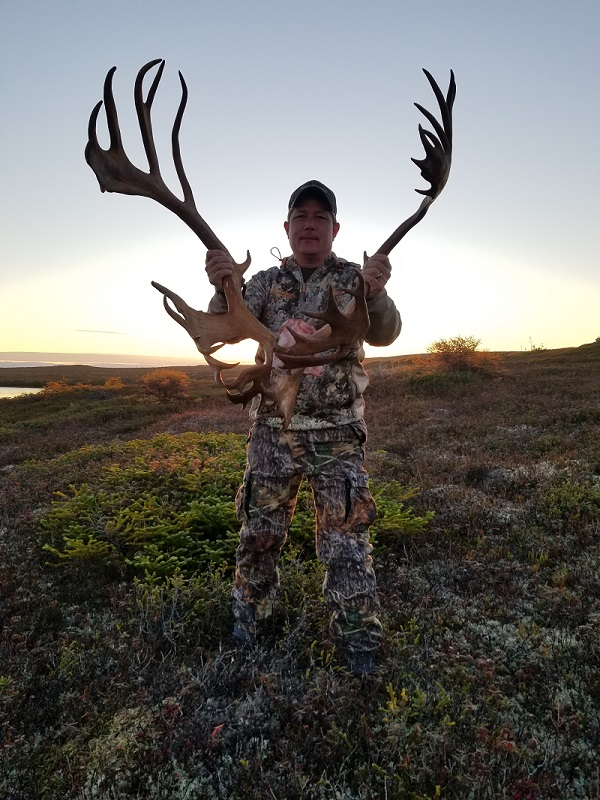 Man holding up antlers from a moose