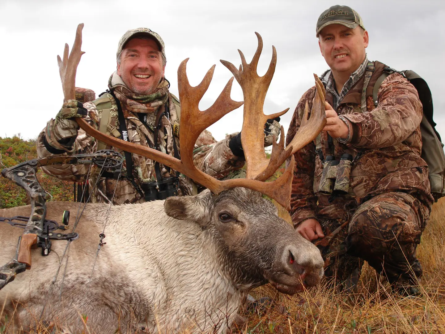 Two men holding the antlers of a moose