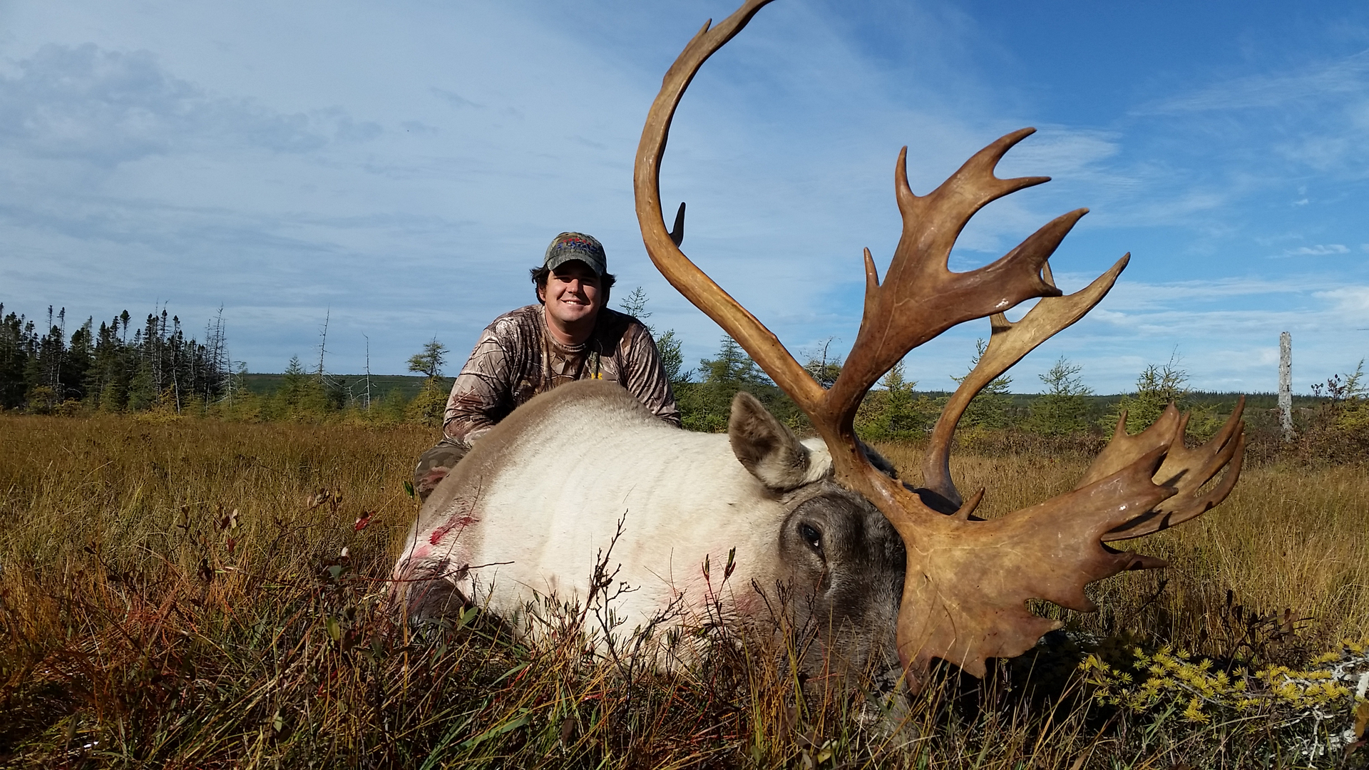 Hunter posing with large antlered caribou