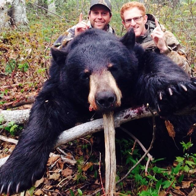 Two men posing for a photo with their hunted black bear