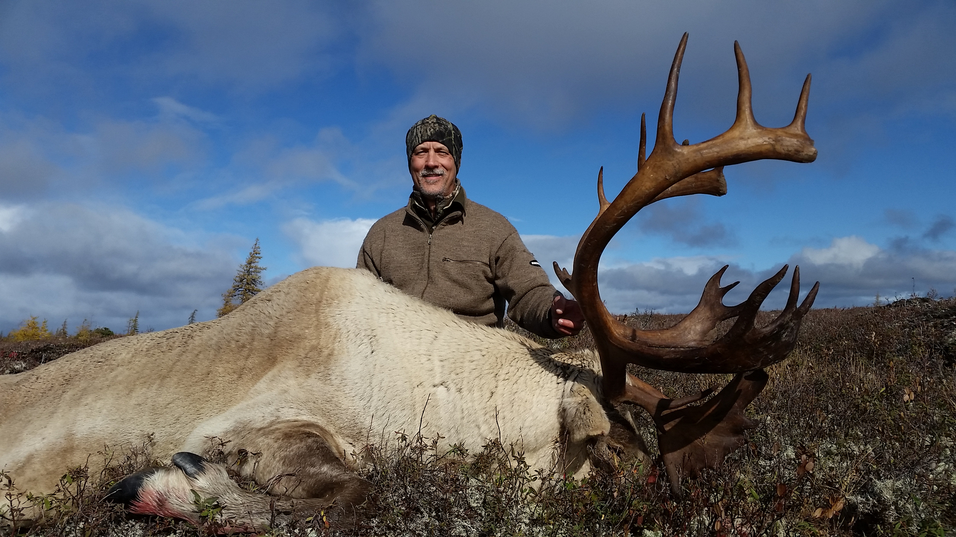 Man smiling for the camera with his hunted moose