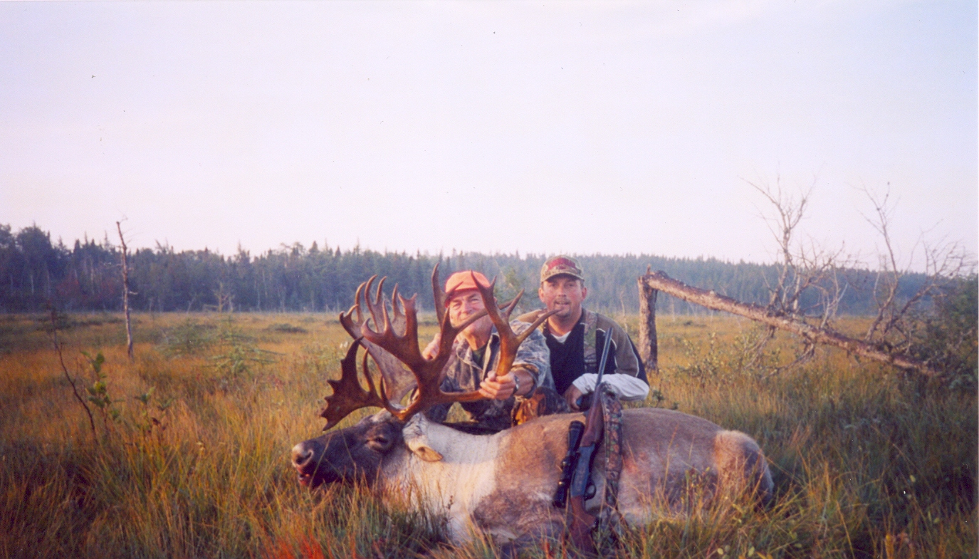Two men posing for a photo with their hunting rifle and hunted moose