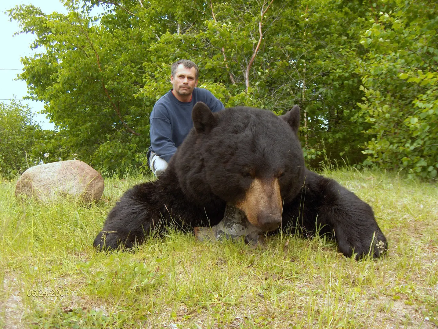 Man with a large black bear in a field