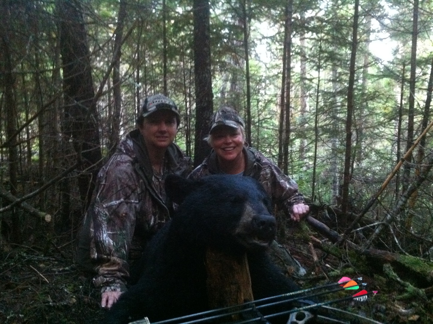 Two hunters in a forest with their hunted bear