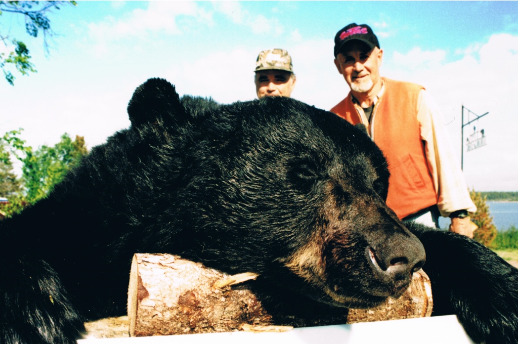Two men behind a hunted black bear