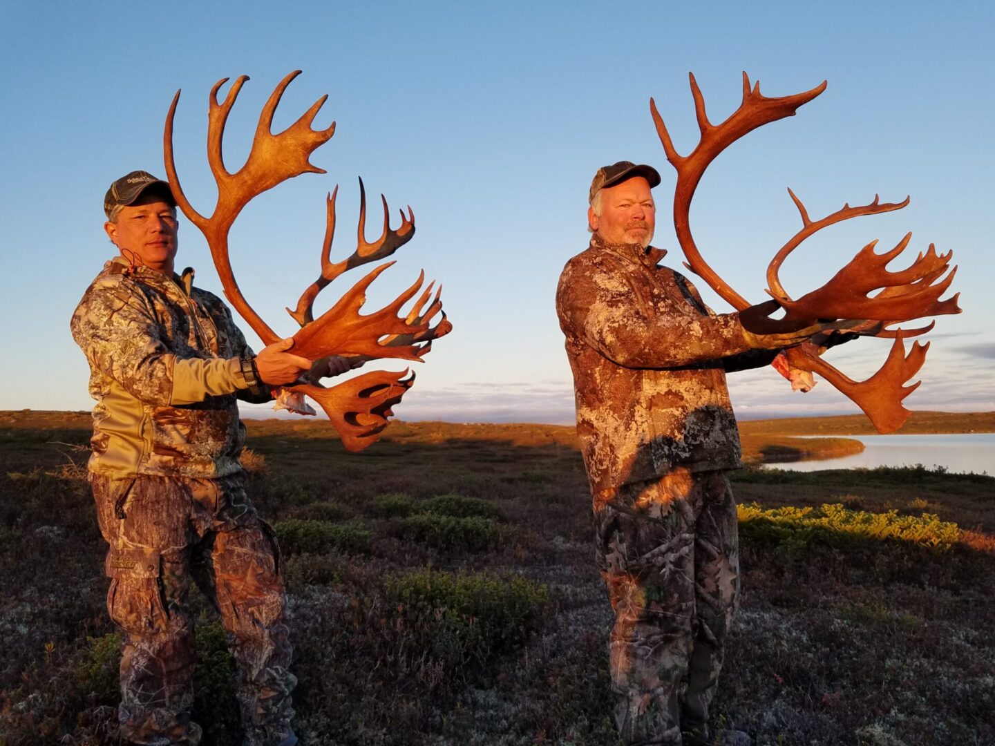 Two men holding antlers on a field