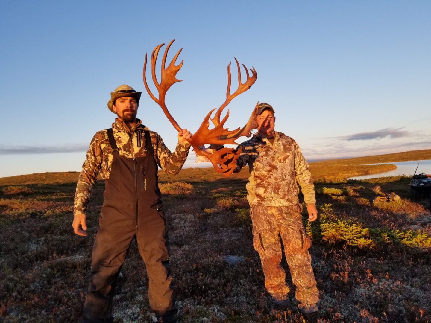two men holding an antler in the fields